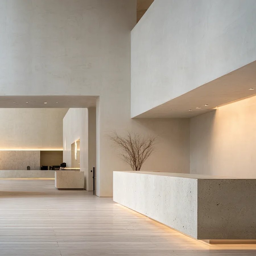 Un grand hall aux murs de pierre claire et son comptoir d’accueil
